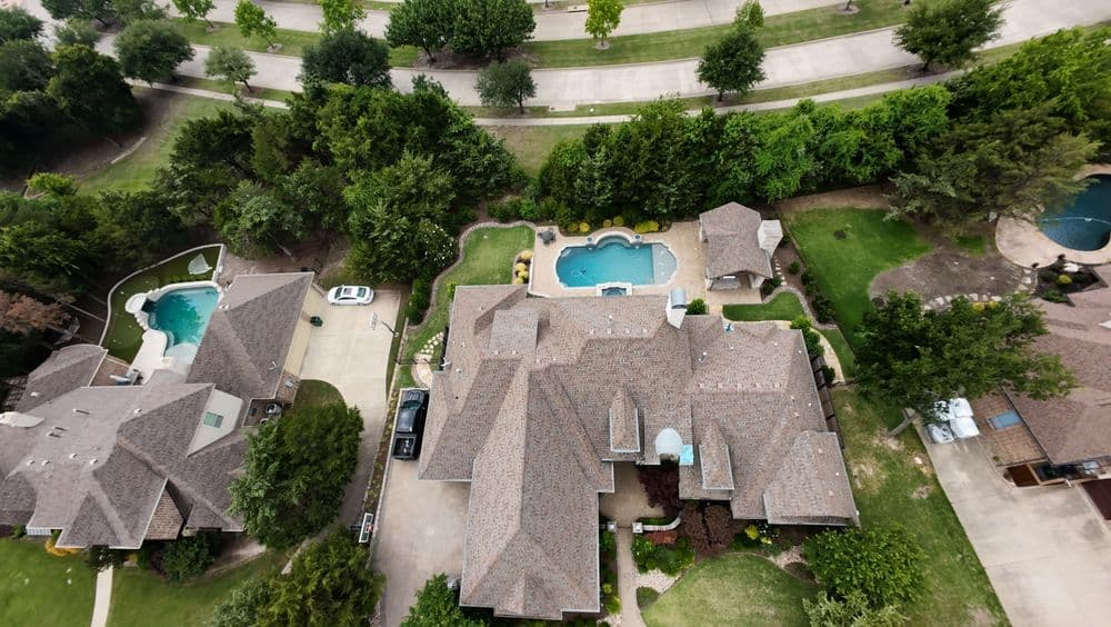 Aerial view of luxury homes with pools and landscaped yards in a suburban neighborhood.