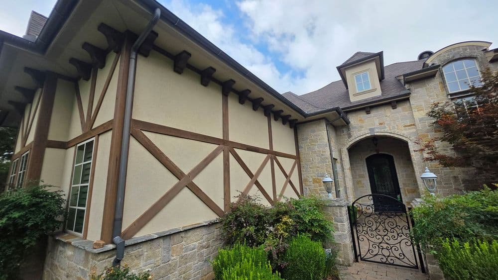 Elegant home exterior featuring stone and stucco design with decorative wooden beams.